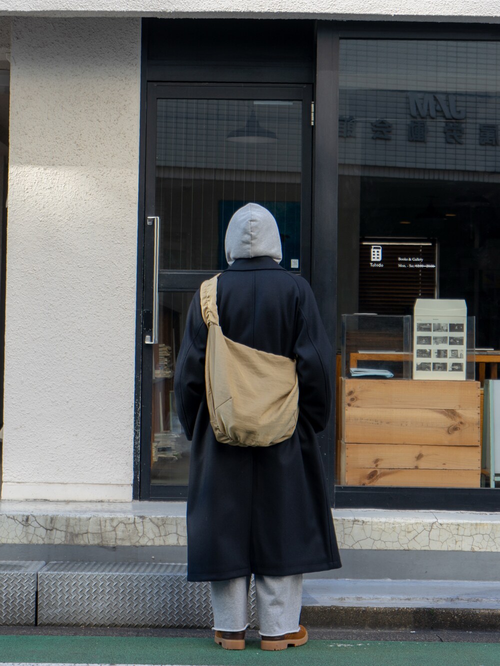 ブラック系のステンカラーコート、グレー系のスウェットパンツ、ベージュ系のショルダーバッグを着用したメンズの冬コーディネートの3枚目の写真