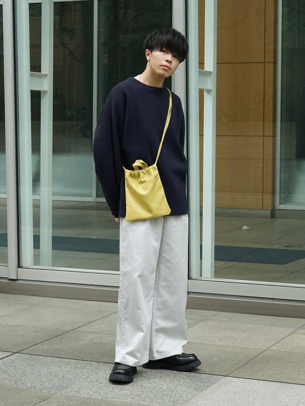 グリーン系のニット/セーター、ホワイト系のチノパンツ、イエロー系のショルダーバッグを着用したメンズの秋コーディネートの2枚目の写真