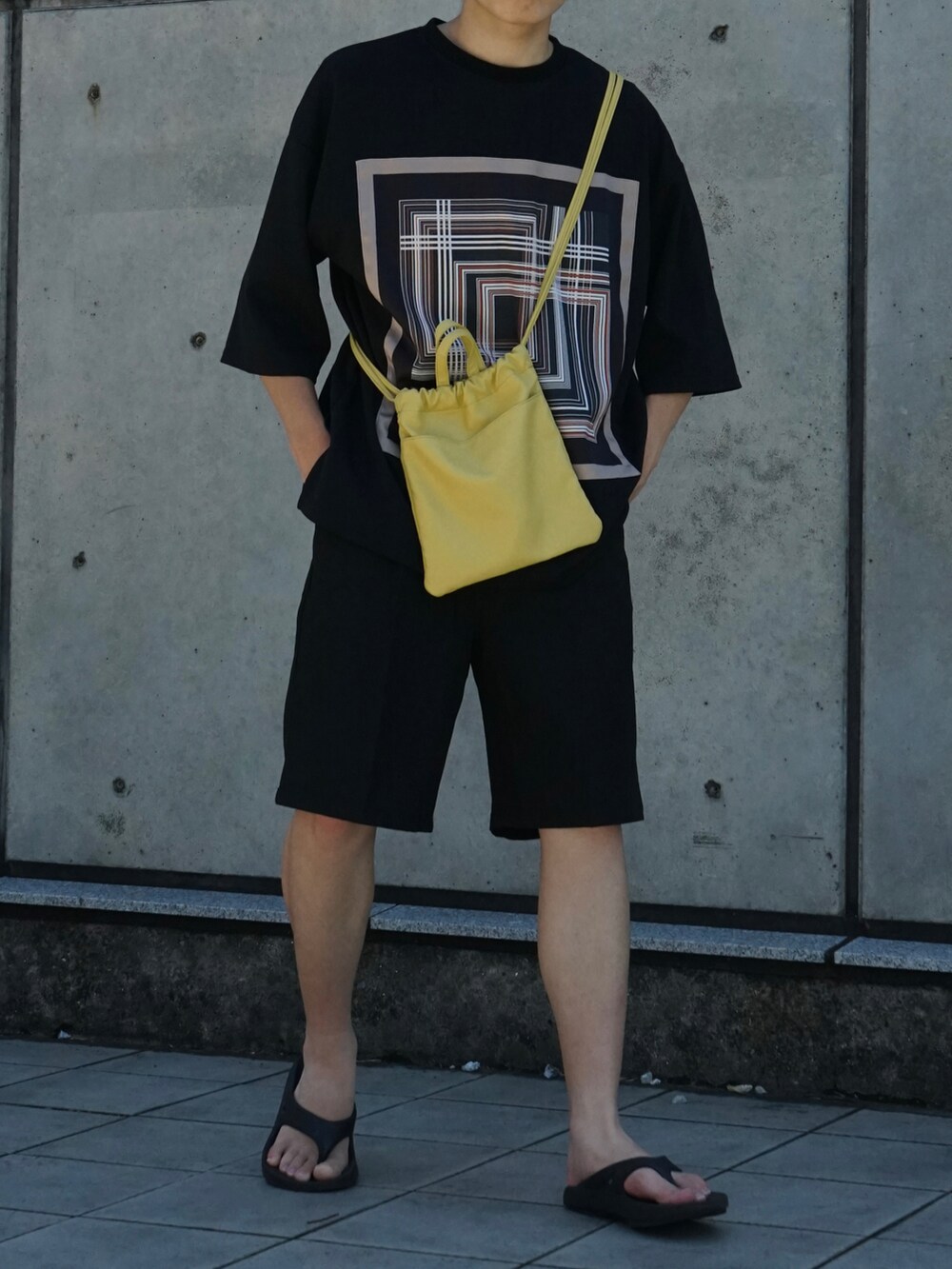 ブラック系のTシャツ/カットソー、ブラック系のスラックス、イエロー系のショルダーバッグを着用したメンズの夏コーディネートの4枚目の写真