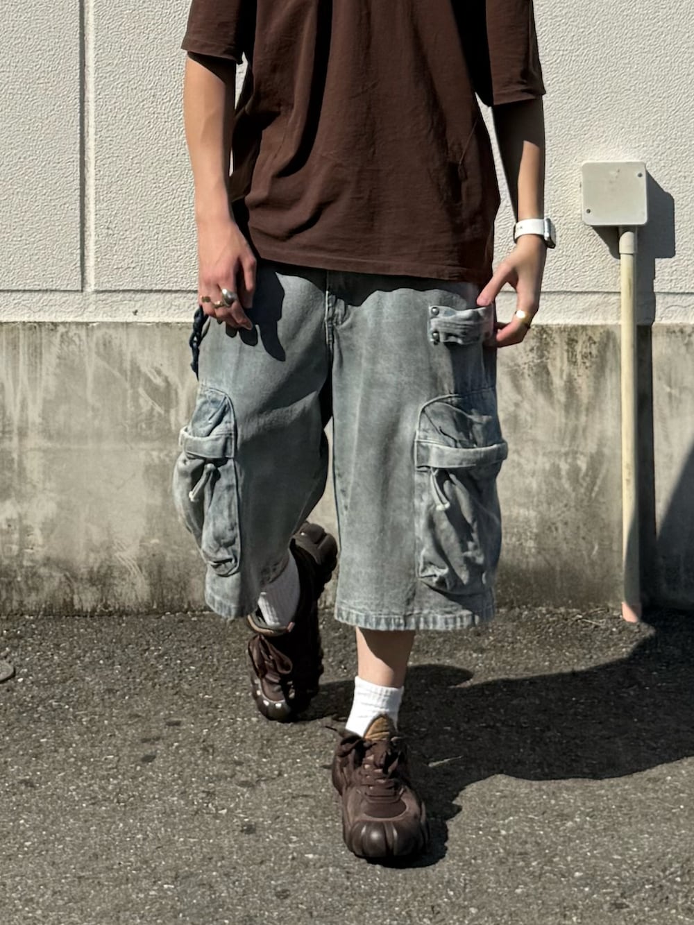 ブラウン系のTシャツ/カットソー、ブルー系のデニムパンツ、ブラウン系のスニーカーを着用したメンズの夏コーディネートの4枚目の写真