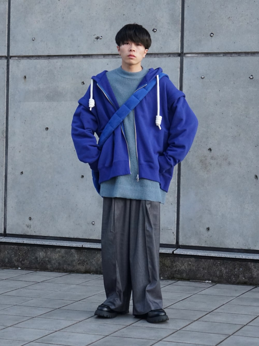 ブルー系のパーカー、ブルー系のニット/セーター、グレー系のスラックスを着用したメンズの秋コーディネートの2枚目の写真