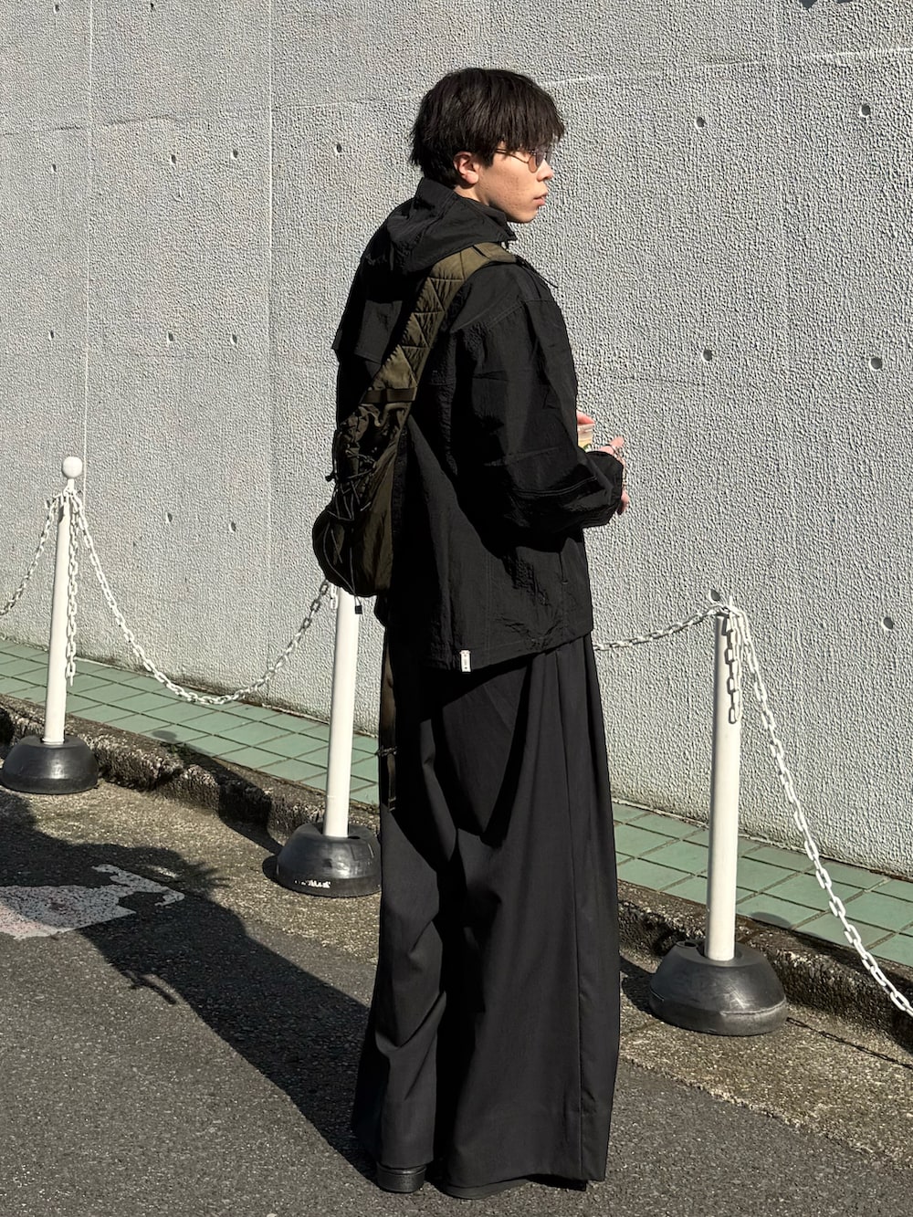 ブラック系のその他アウター、グリーン系のバックパック/リュック、グレー系のスラックスを着用したメンズの春コーディネートの2枚目の写真