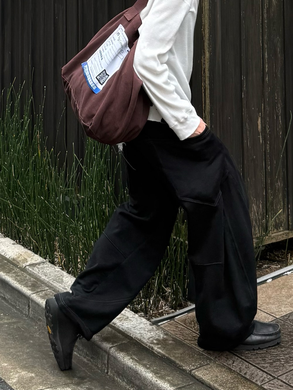 ホワイト系のTシャツ/カットソー、ブラック系のスウェットパンツ、ブラウン系のトートバッグを着用したメンズの秋コーディネートの2枚目の写真