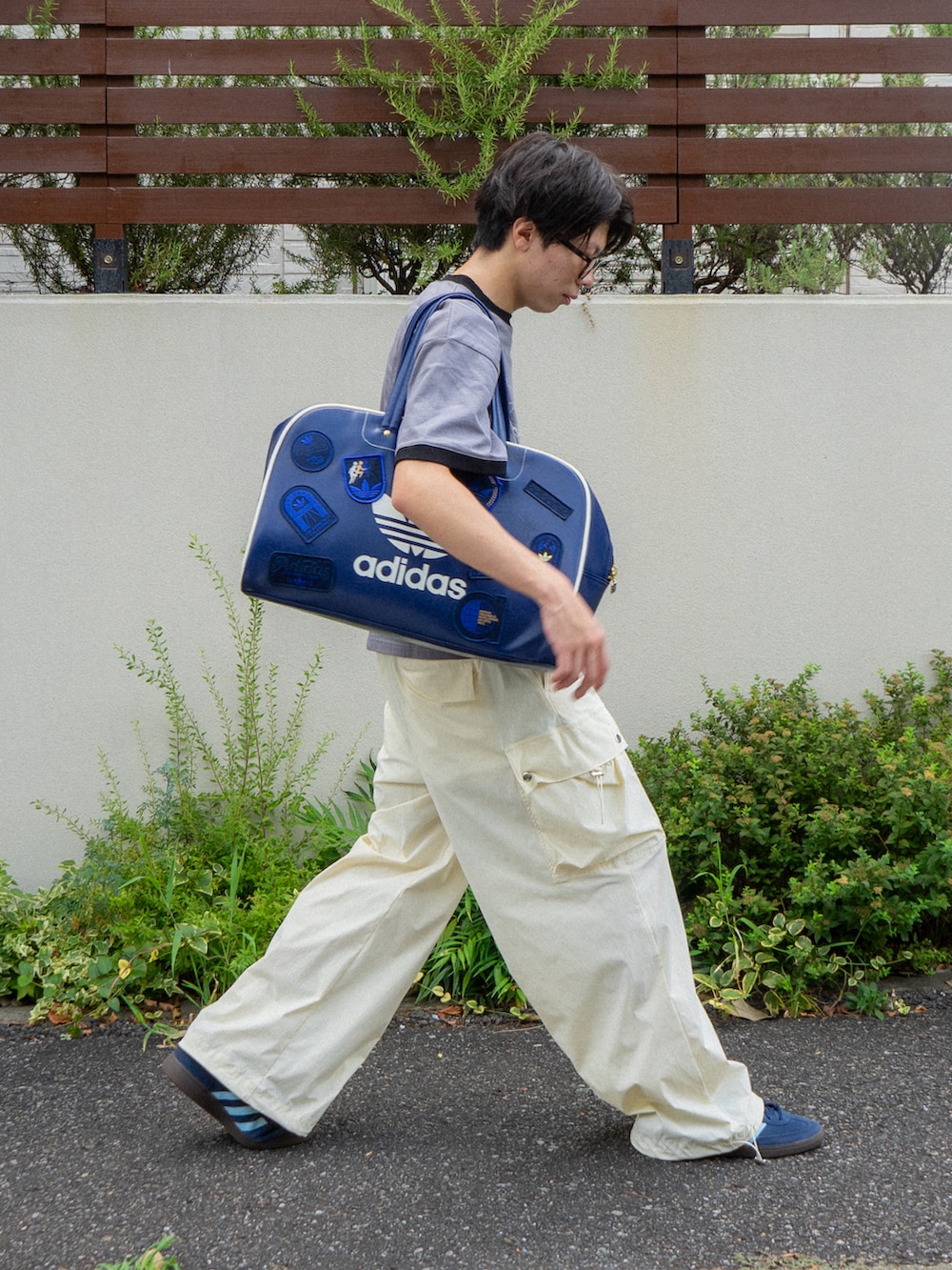 グレー系のTシャツ/カットソー、ブルー系のボストンバッグ、ホワイト系のカーゴパンツを着用したメンズの夏コーディネートの2枚目の写真