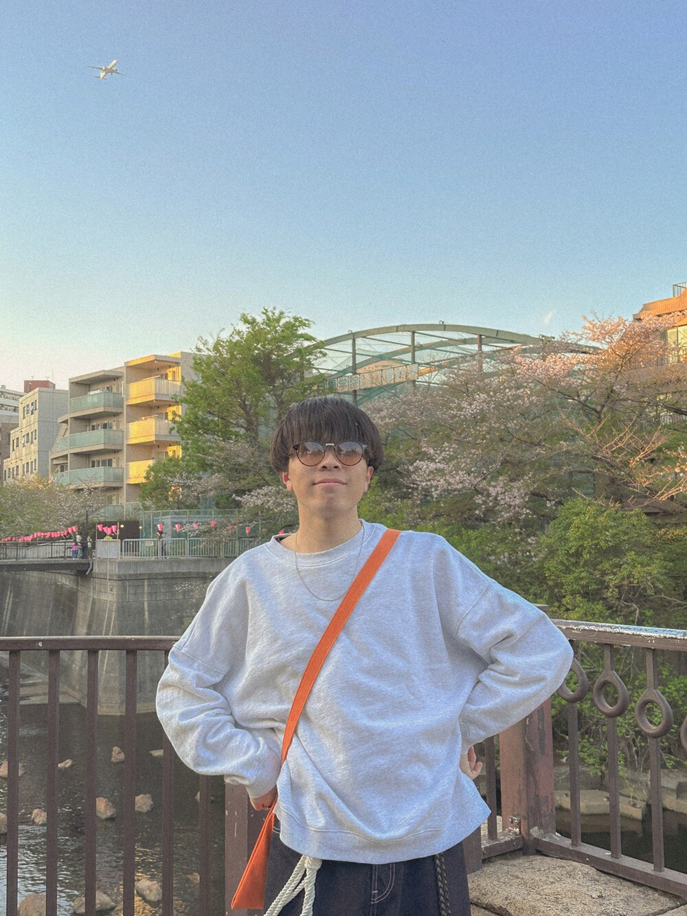 グレー系のスウェット、ブルー系のデニムパンツ、オレンジ系のショルダーバッグを着用したメンズの春コーディネートの3枚目の写真