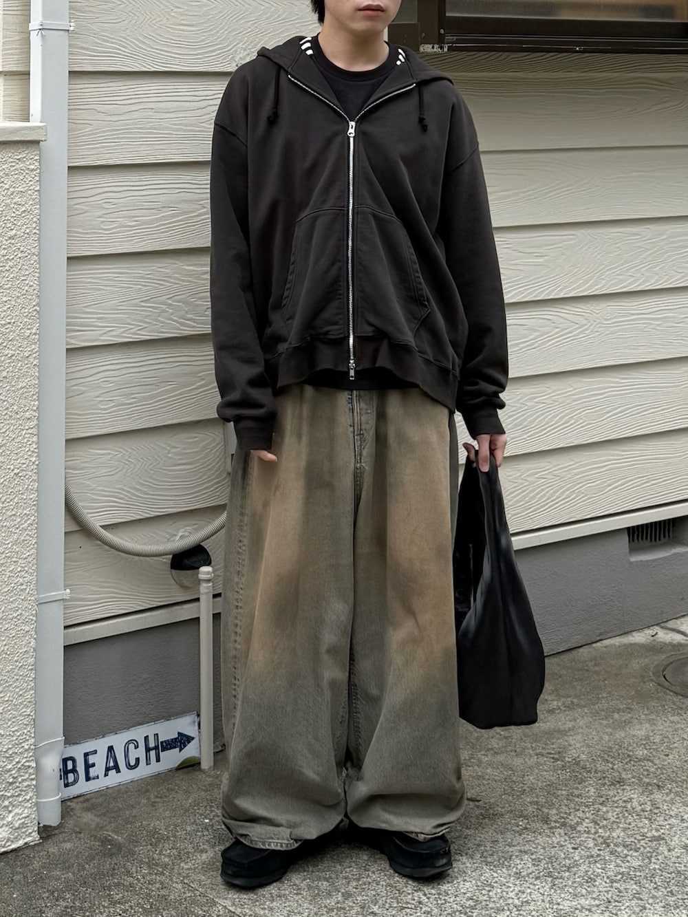 ブラック系のパーカー、ブラック系のTシャツ/カットソー、ブルー系のデニムパンツを着用したメンズの春コーディネートの2枚目の写真