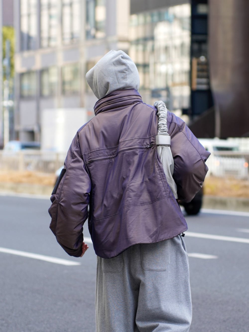 パープル系のブルゾン、グレー系のパーカー、グレー系のスウェットパンツを着用したメンズの冬コーディネートの4枚目の写真