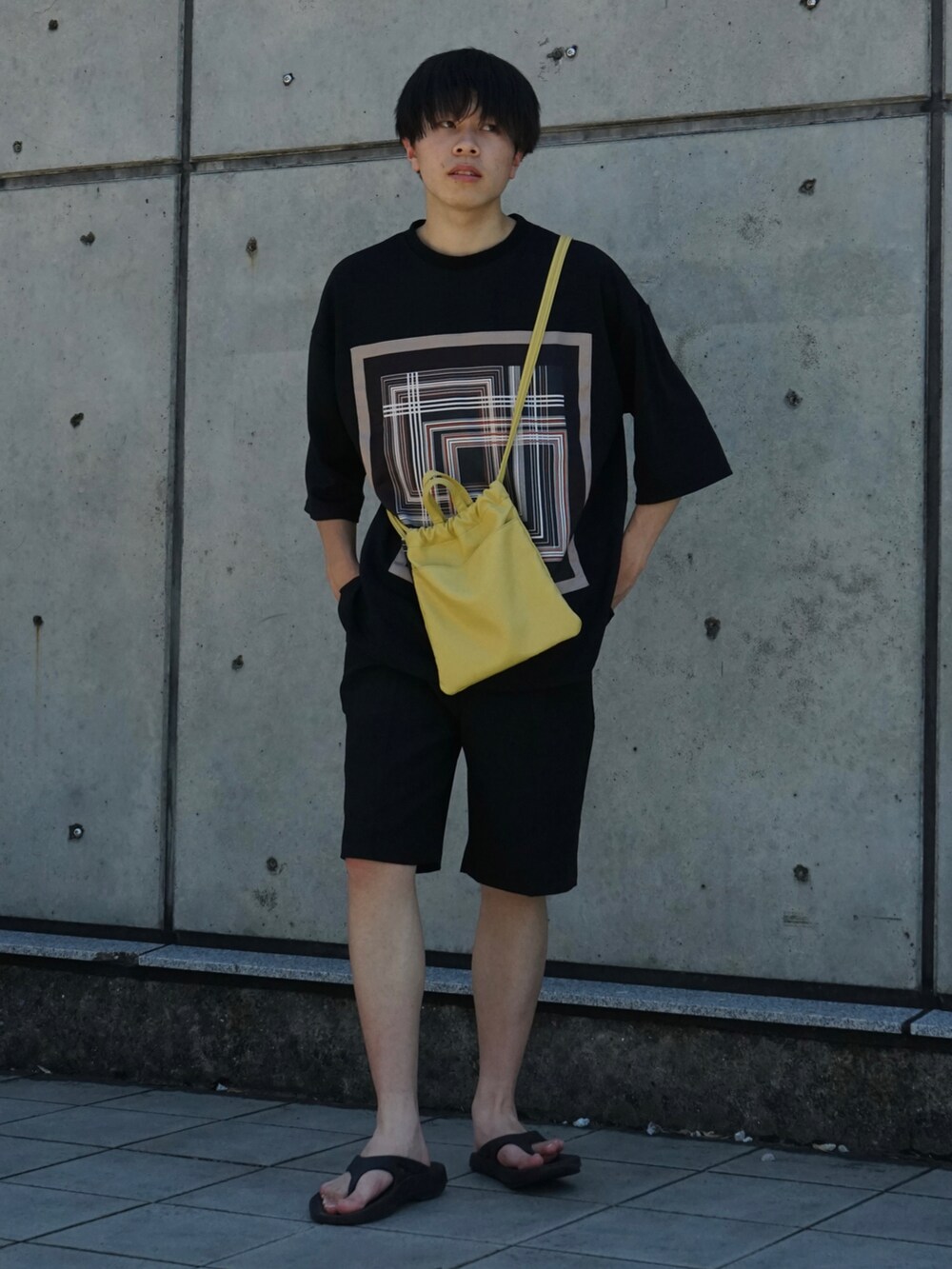 ブラック系のTシャツ/カットソー、ブラック系のスラックス、イエロー系のショルダーバッグを着用したメンズの夏コーディネートの3枚目の写真
