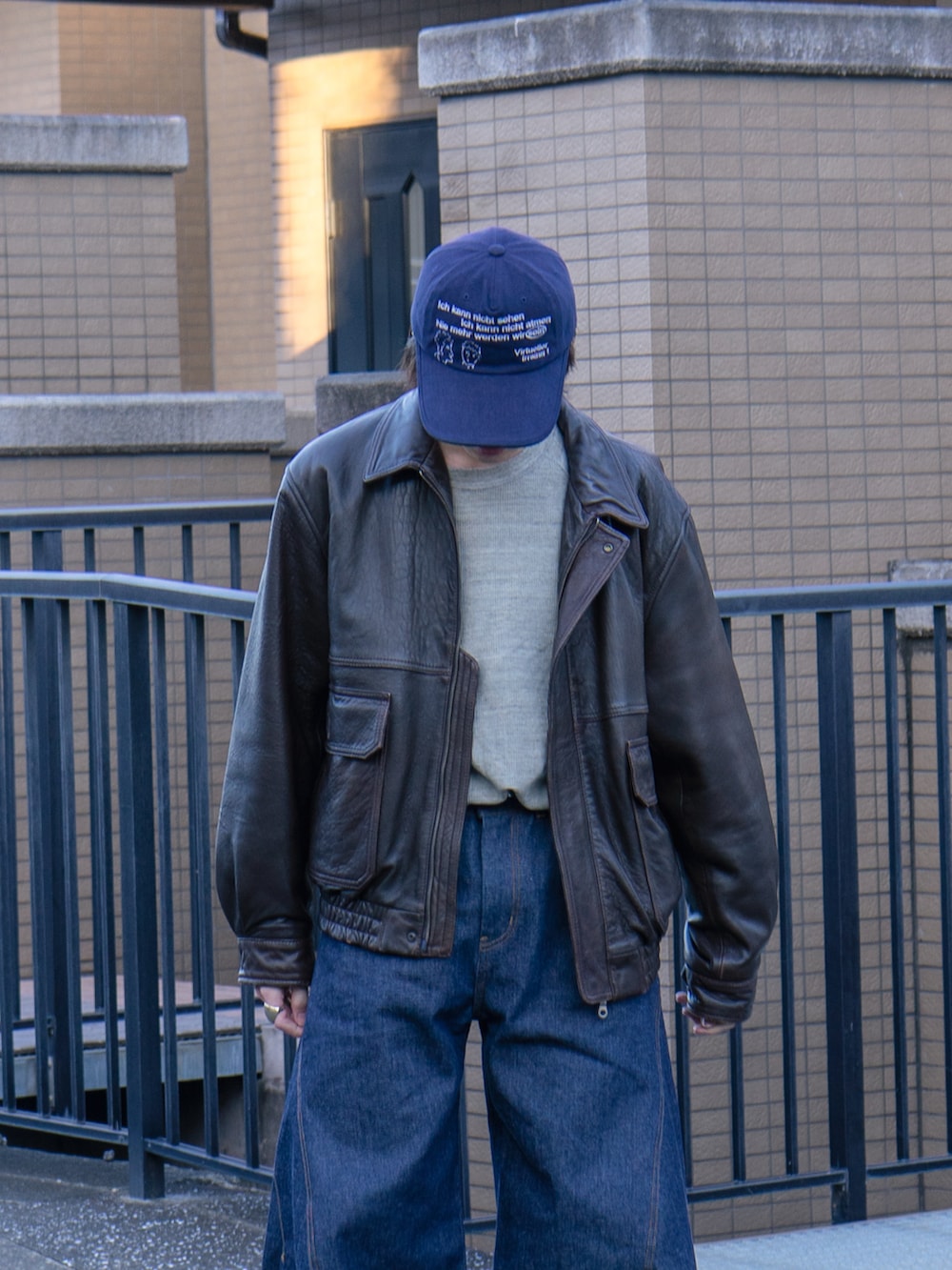 ブラウン系のブルゾン、グレー系のTシャツ/カットソー、ブルー系のデニムパンツを着用したメンズの冬コーディネートの4枚目の写真