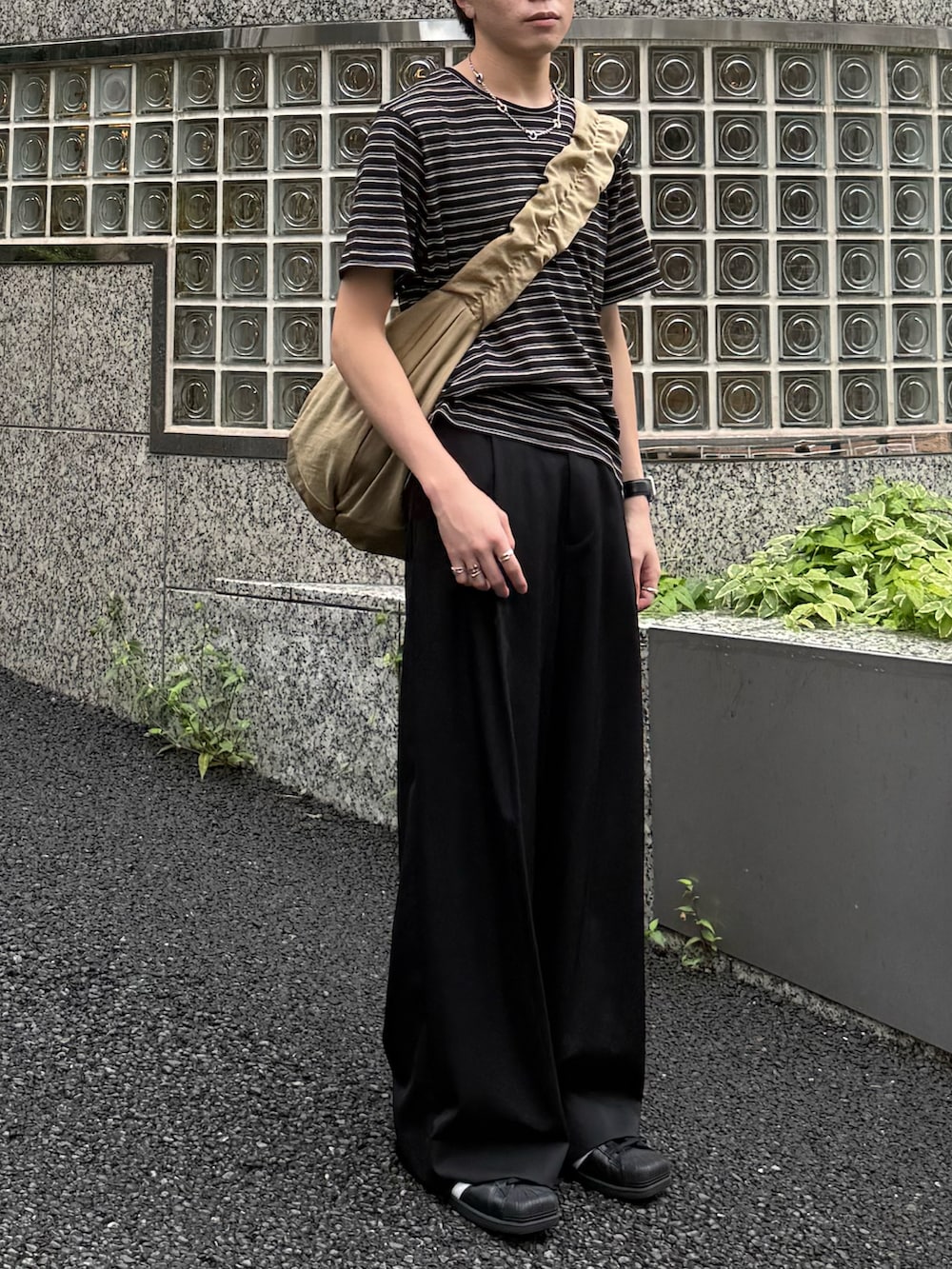 ブラック系のTシャツ/カットソー、ブラック系のスラックス、ベージュ系のショルダーバッグを着用したメンズの夏コーディネートの4枚目の写真