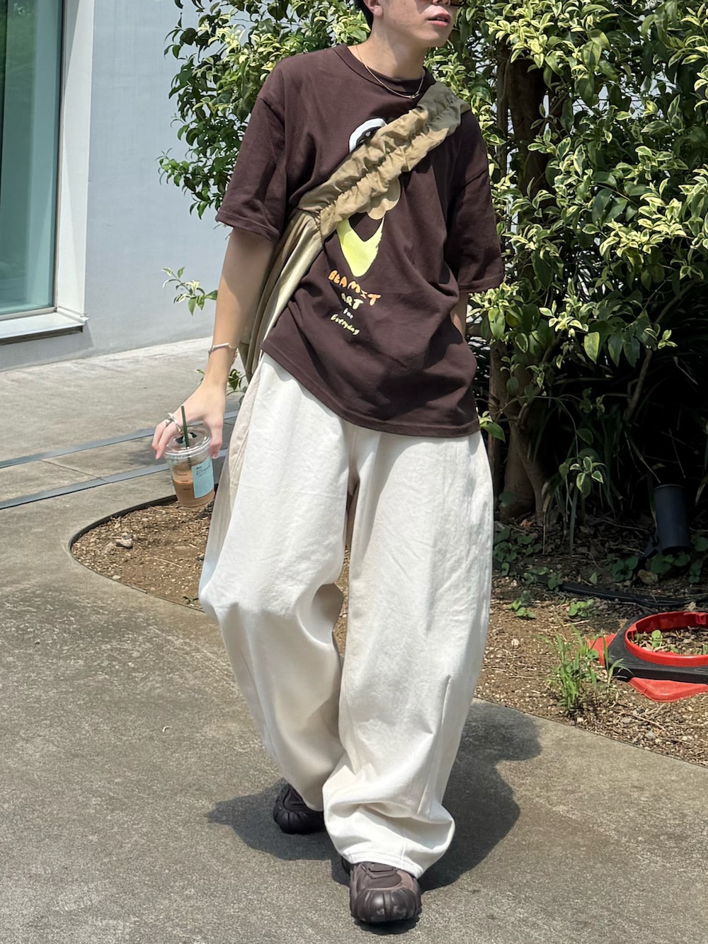 ブラウン系のTシャツ/カットソー、ベージュ系のショルダーバッグ、ホワイト系のデニムパンツを着用したメンズの秋コーディネートの5枚目の写真