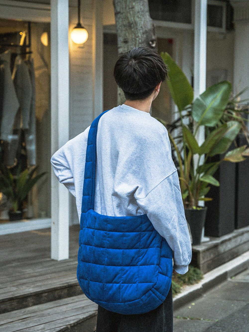グレー系のスウェット、ブラック系のデニムパンツ、ブルー系のショルダーバッグを着用したメンズの春コーディネートの4枚目の写真