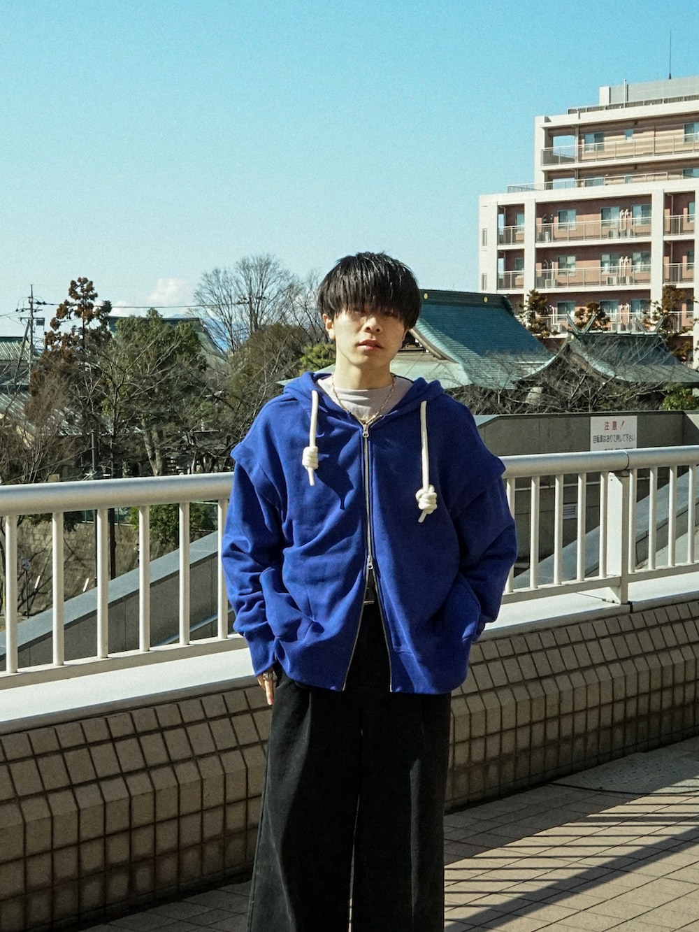 ブルー系のパーカー、ブラック系のデニムパンツ、ブラック系のスニーカーを着用したメンズの春コーディネートの4枚目の写真