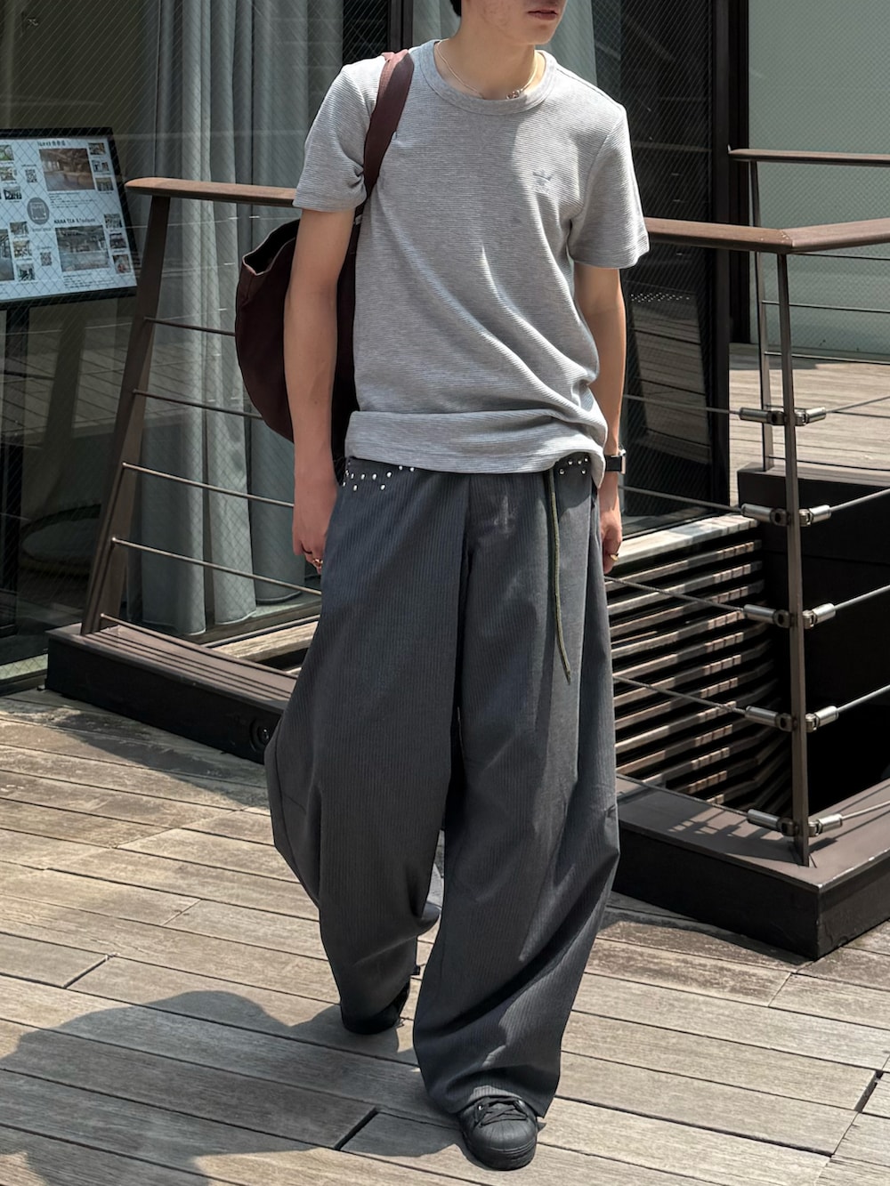 グレー系のTシャツ/カットソー、グレー系のスラックス、ブラウン系のトートバッグを着用したメンズの夏コーディネートの4枚目の写真