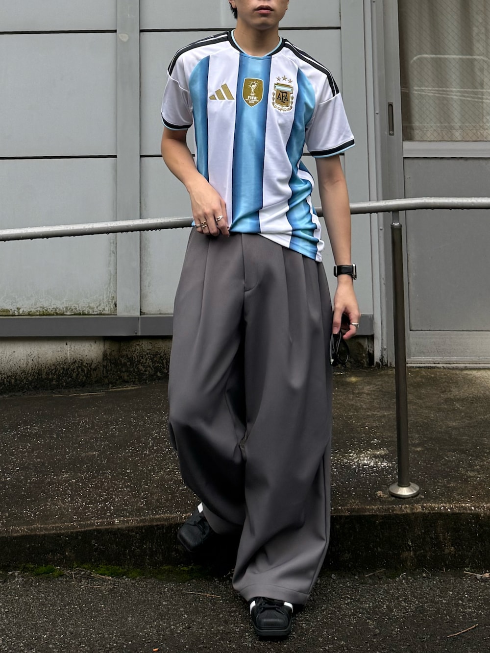 ホワイト系のTシャツ/カットソー、グレー系のパンツ、ブラック系のスニーカーを着用したメンズの夏コーディネートの4枚目の写真