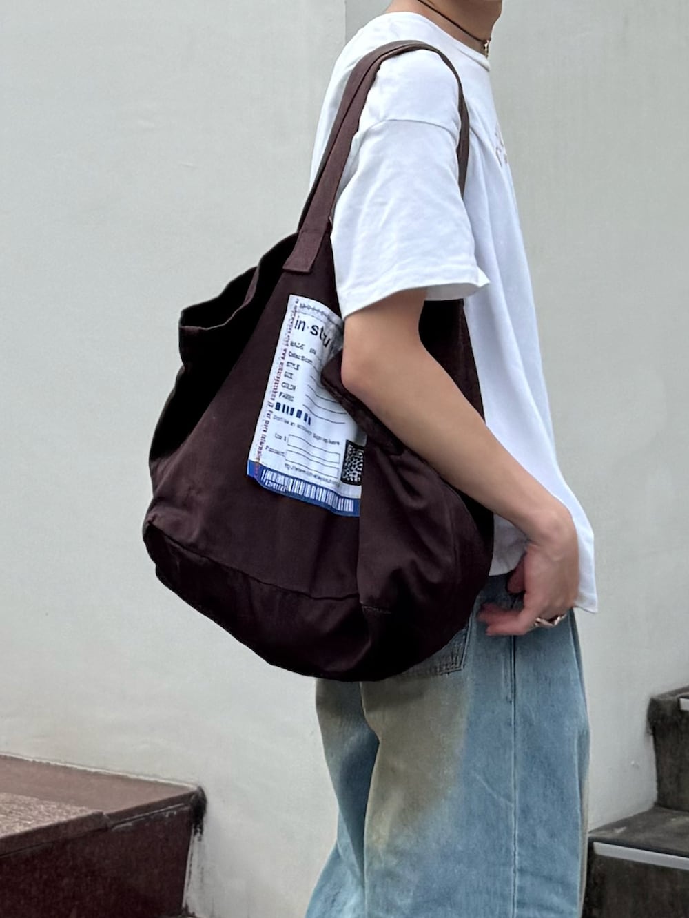 ホワイト系のTシャツ/カットソー、ブルー系のデニムパンツ、ブラウン系のトートバッグを着用したメンズの夏コーディネートの2枚目の写真