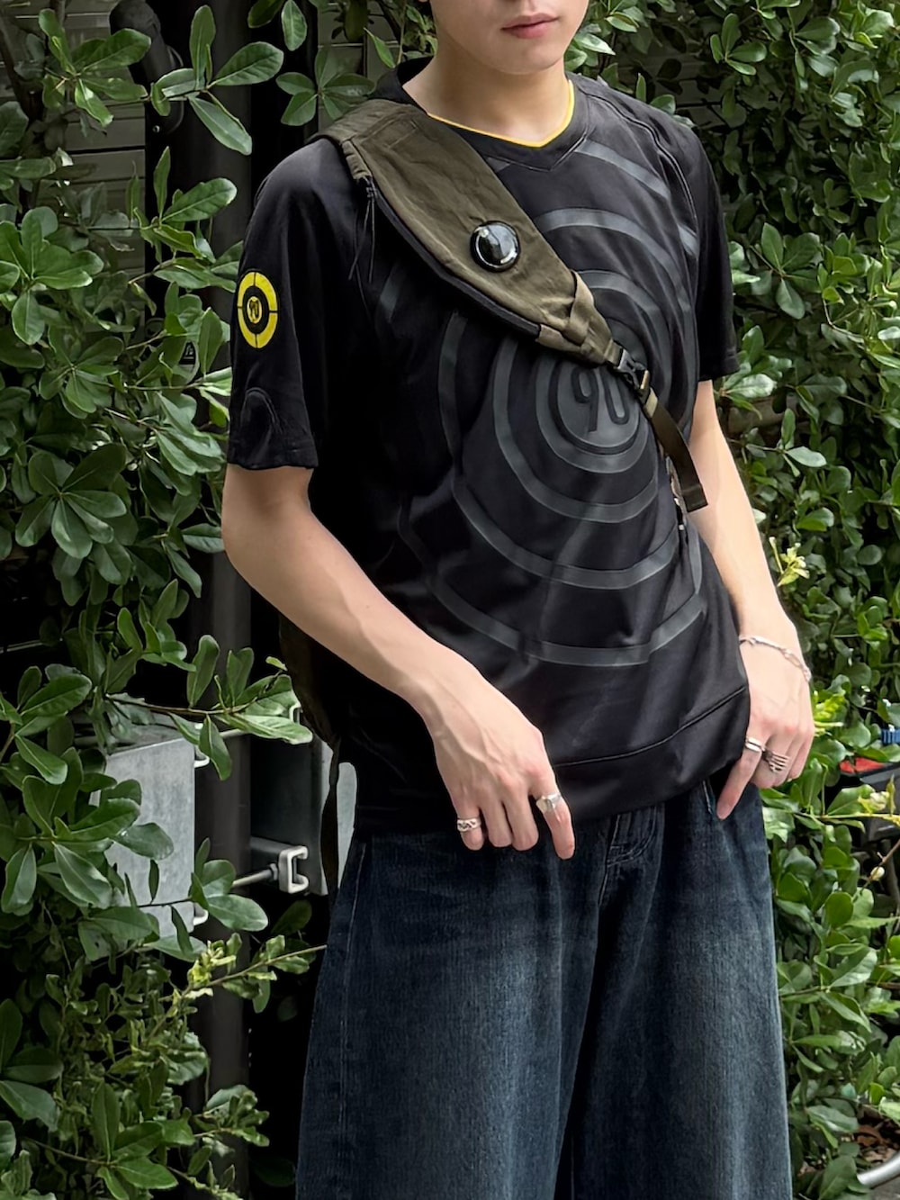 ブラック系のジャージ、ブルー系のデニムパンツ、グリーン系のバックパック/リュックを着用したメンズの夏コーディネートの2枚目の写真