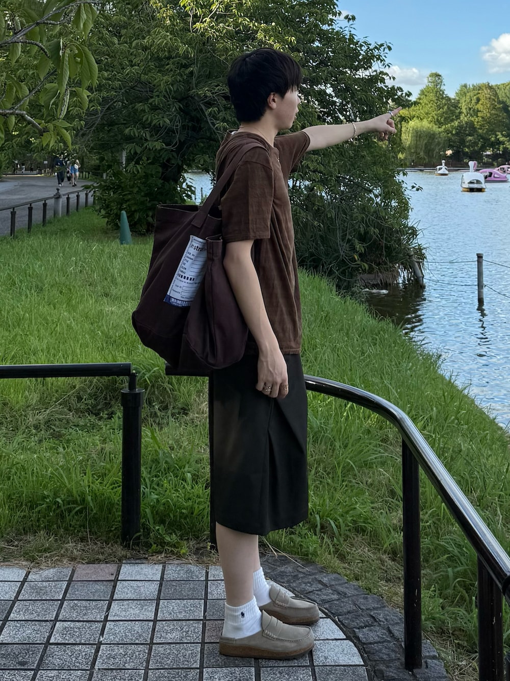 ブラウン系のTシャツ/カットソー、グリーン系のスラックス、ブラウン系のトートバッグを着用したメンズの夏コーディネートの2枚目の写真