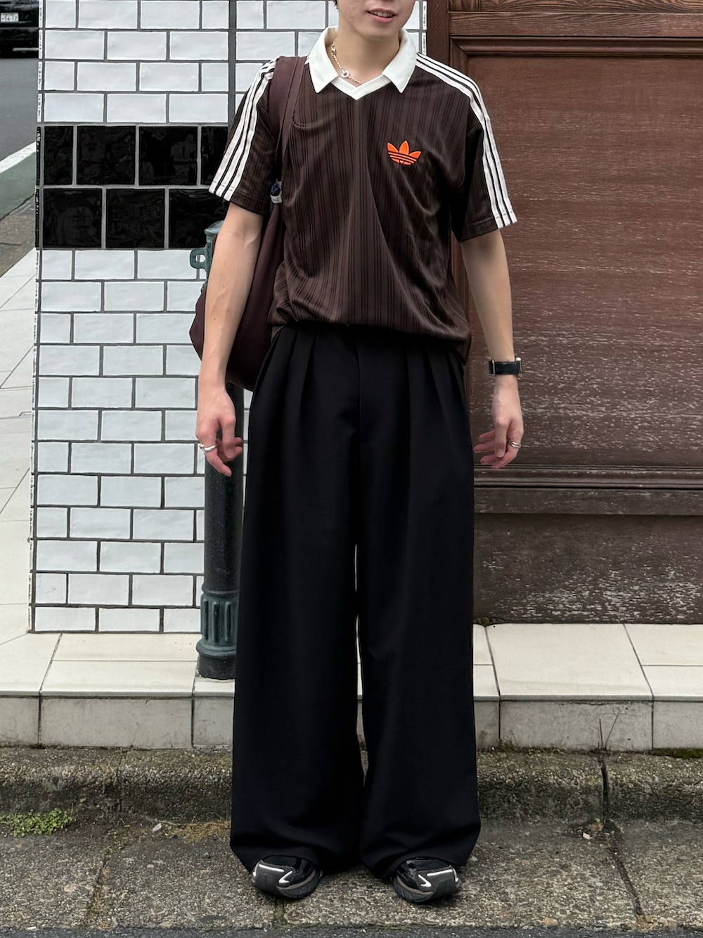 ブラウン系のTシャツ/カットソー、ブラック系のスラックス、ブラウン系のトートバッグを着用したメンズの夏コーディネートの5枚目の写真