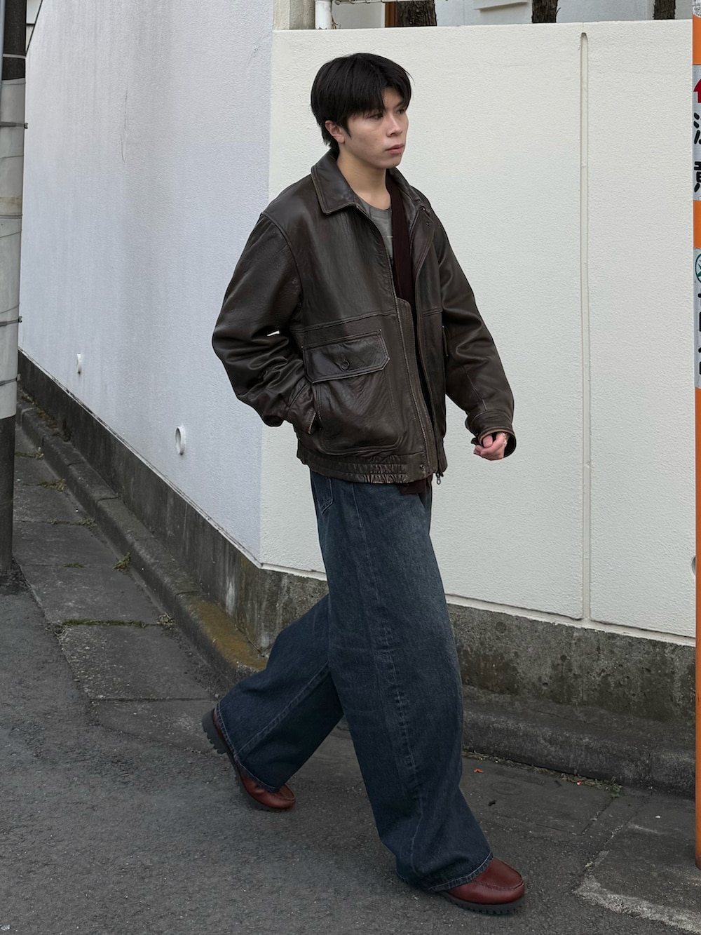 ホワイト系のTシャツ/カットソー、ブラウン系のブルゾン、ブルー系のデニムパンツを着用したメンズの冬コーディネートの2枚目の写真