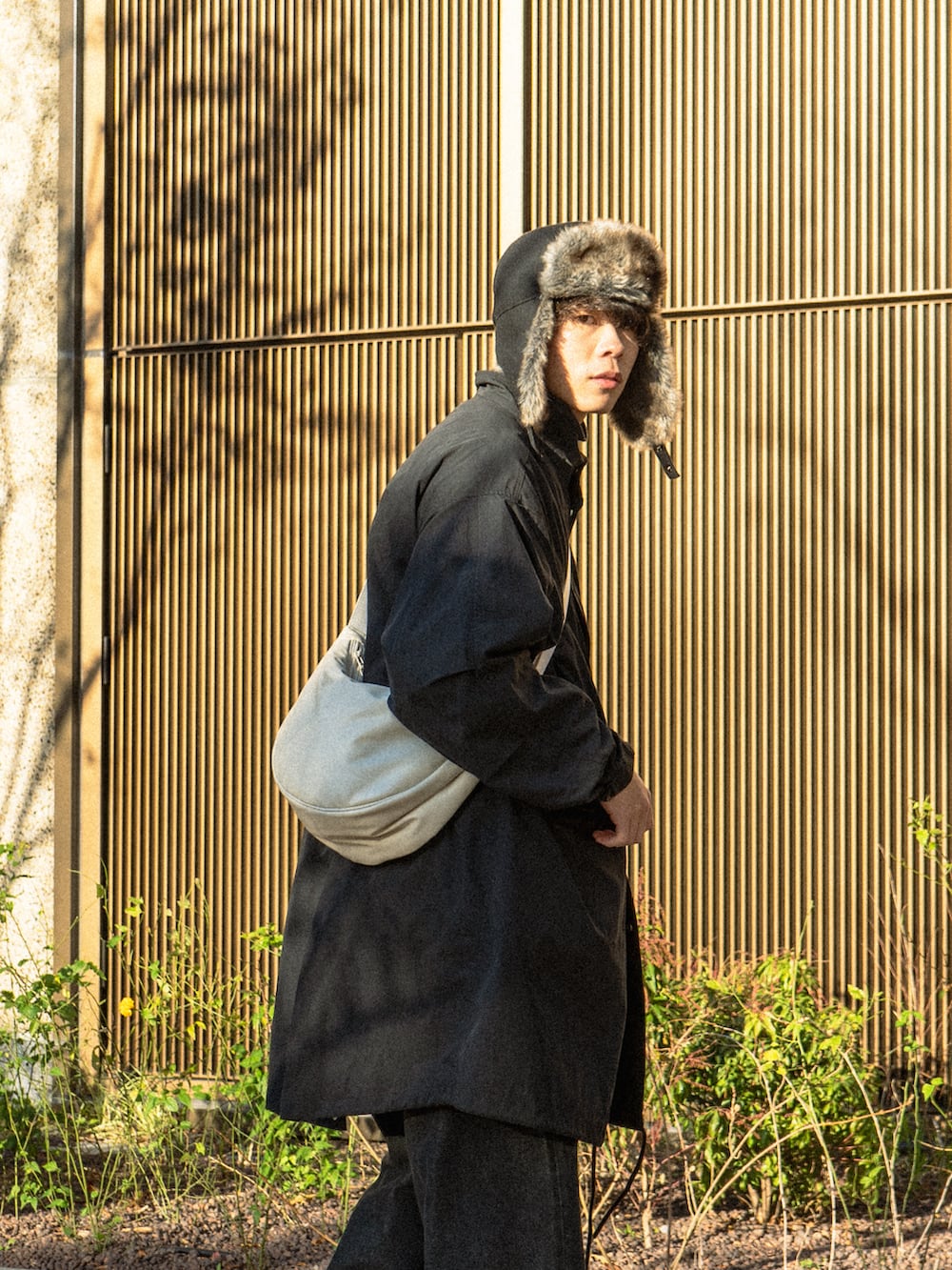 ブラック系のモッズコート、ブラック系のデニムパンツ、ブラック系のブーツを着用したメンズの冬コーディネートの3枚目の写真