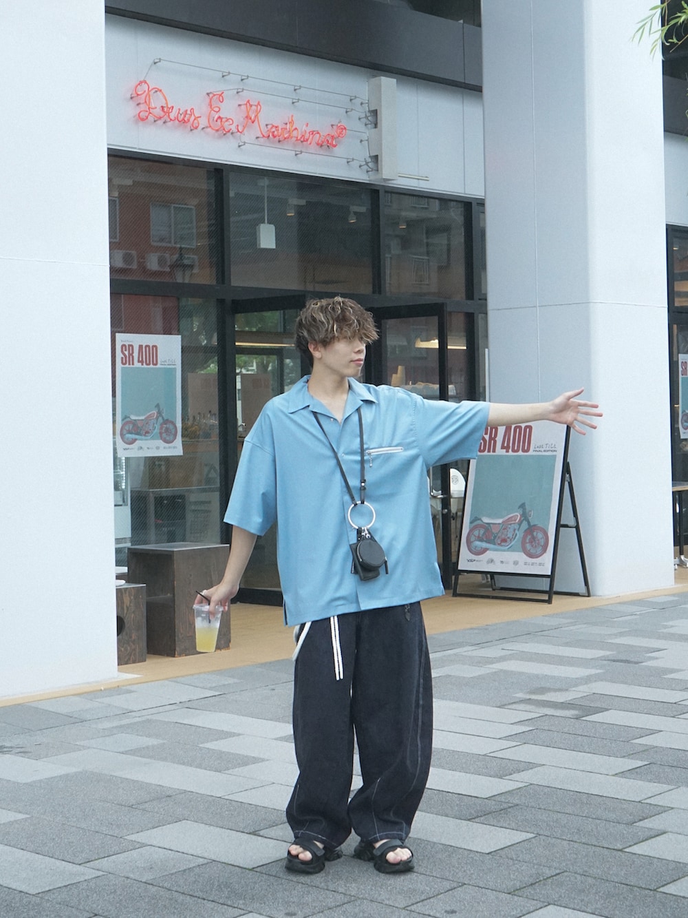 ブルー系のデニムパンツ、ブラック系のショルダーバッグ、ブラック系のサンダルを着用したメンズの夏コーディネートの3枚目の写真