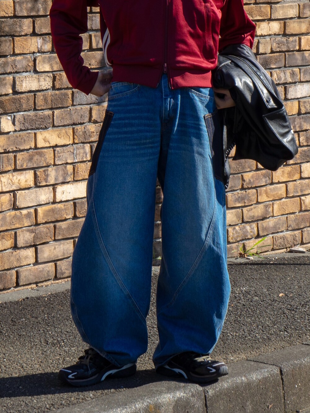 レッド系のその他トップス、ブルー系のデニムパンツ、ブラック系のブルゾンを着用したメンズの秋コーディネートの4枚目の写真