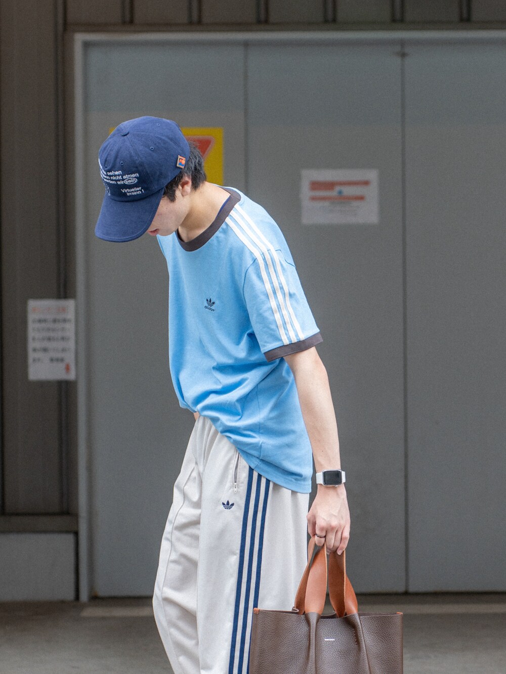ブルー系のTシャツ/カットソー、ホワイト系のその他パンツ、ブラウン系のハンドバッグを着用したメンズの夏コーディネートの4枚目の写真