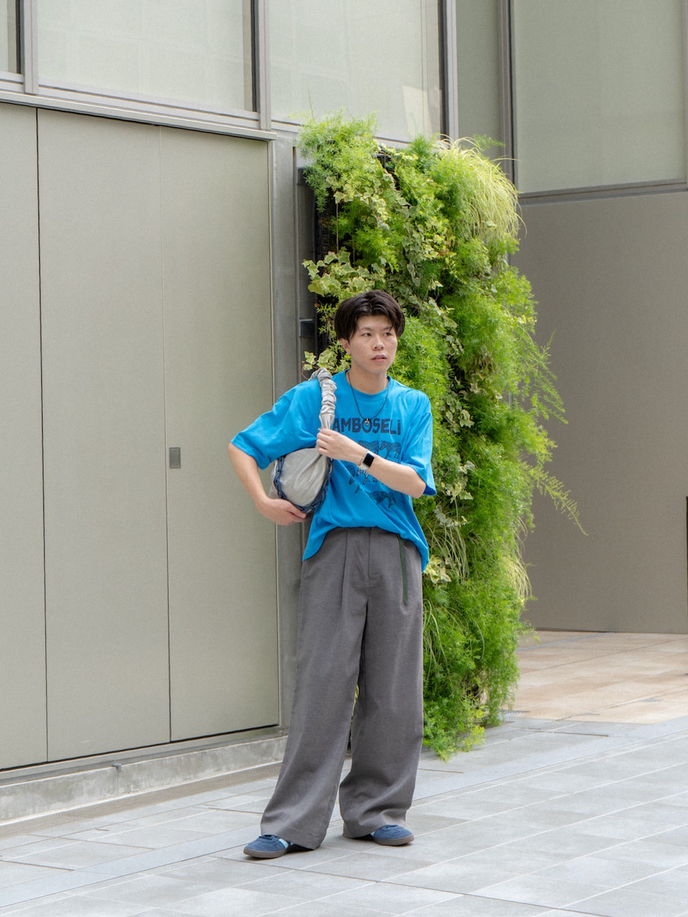 ブルー系のTシャツ/カットソー、グレー系のスラックス、ブルー系のスニーカーを着用したメンズの夏コーディネートの3枚目の写真