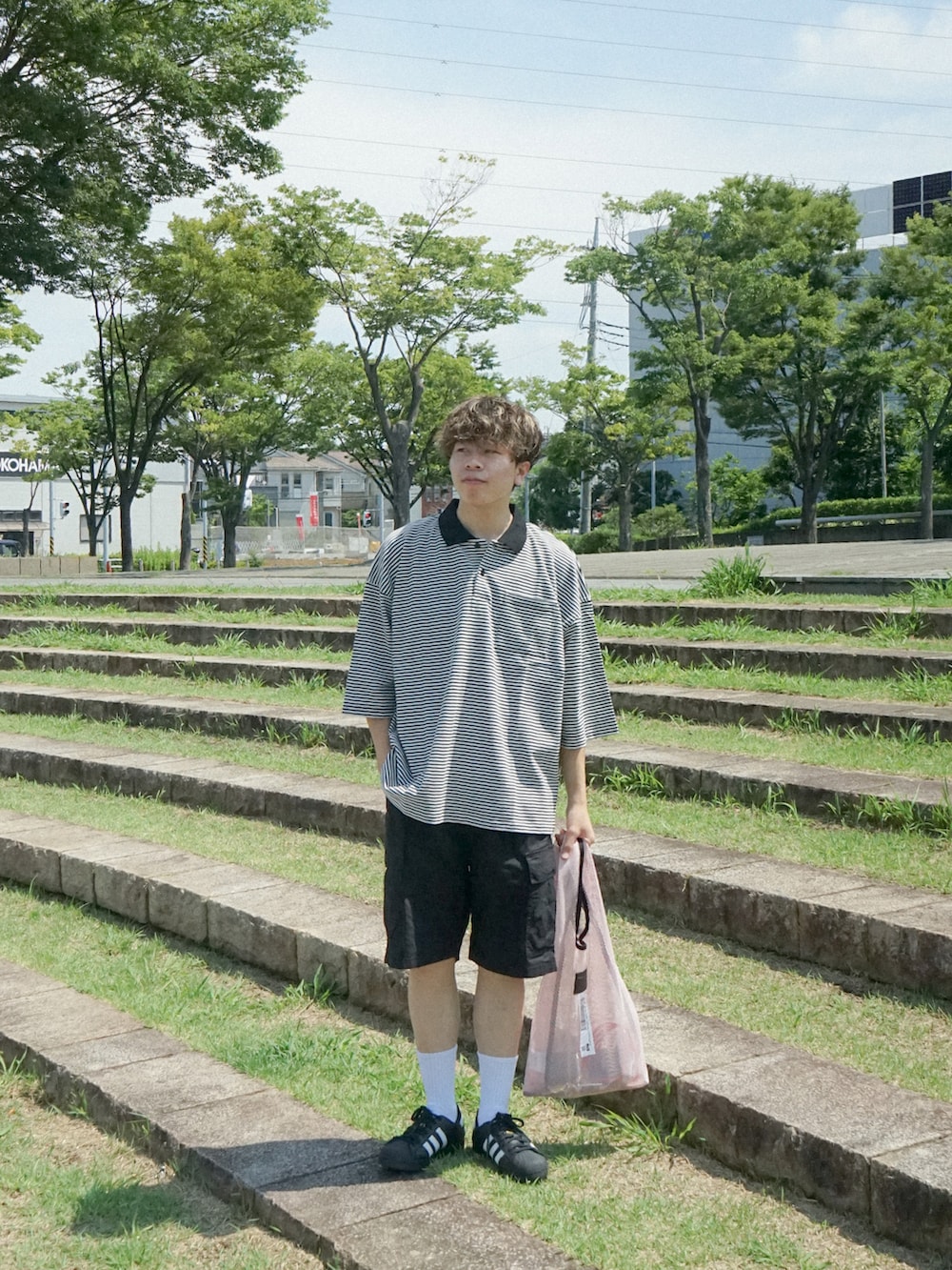 ピンク系のトートバッグ、ブラック系のスニーカー、ブルー系のその他を着用したメンズの夏コーディネートの3枚目の写真