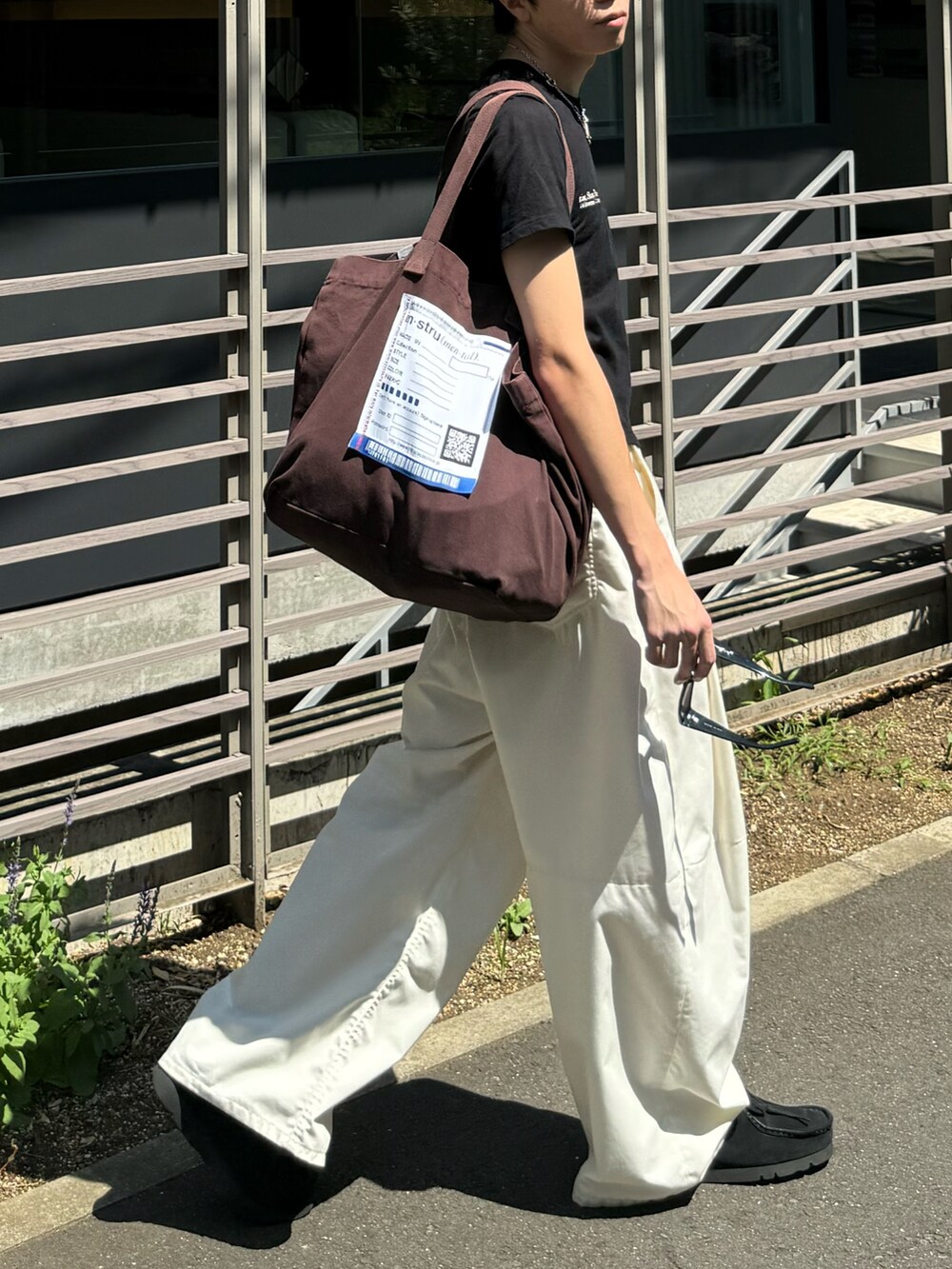 ホワイト系のその他パンツ、ブラウン系のトートバッグ、ブラック系のTシャツ/カットソーを着用したメンズの夏コーディネートの3枚目の写真