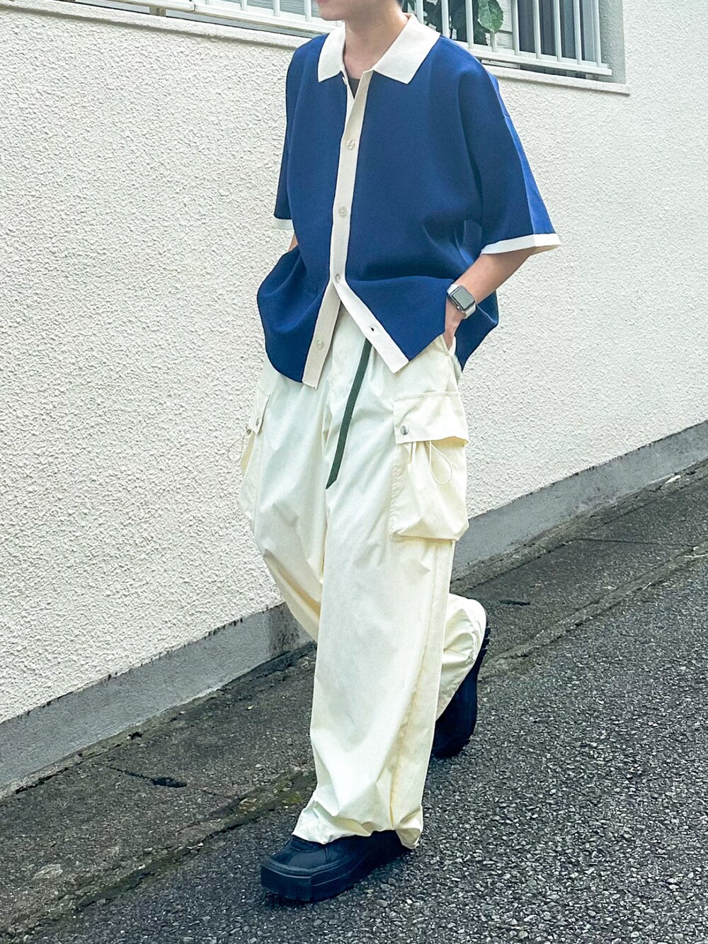ブルー系のポロシャツ、ホワイト系のカーゴパンツ、ブラック系のスニーカーを着用したメンズの秋コーディネートの4枚目の写真