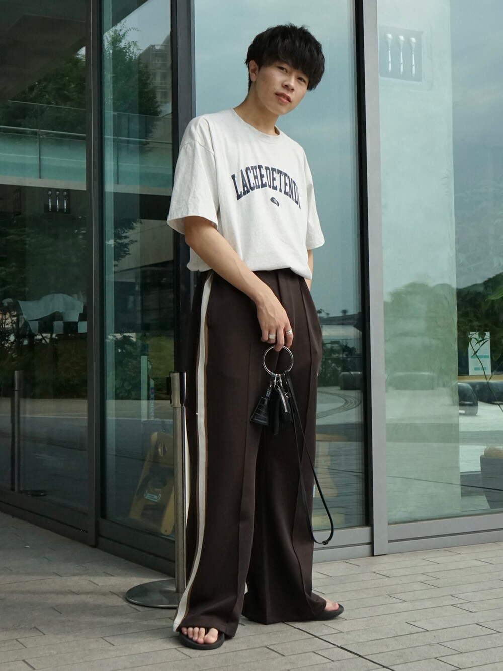 グレー系のTシャツ/カットソー、ブラウン系のその他パンツ、ブラック系のショルダーバッグを着用したメンズの夏コーディネートの3枚目の写真