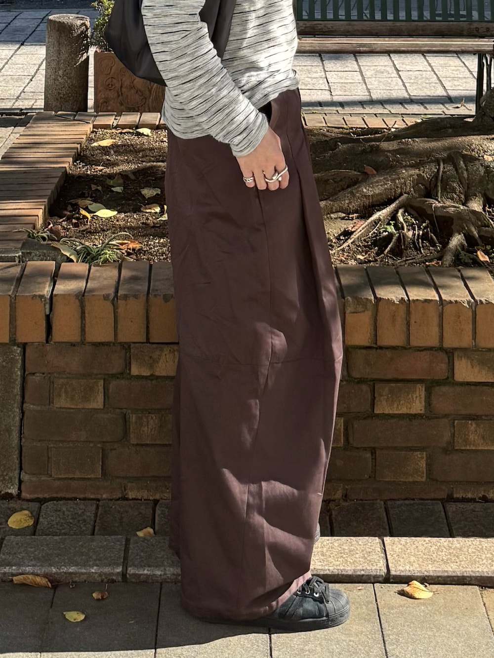 グレー系のTシャツ/カットソー、ブラウン系のその他パンツ、グレー系のハンドバッグを着用したメンズの秋コーディネートの4枚目の写真
