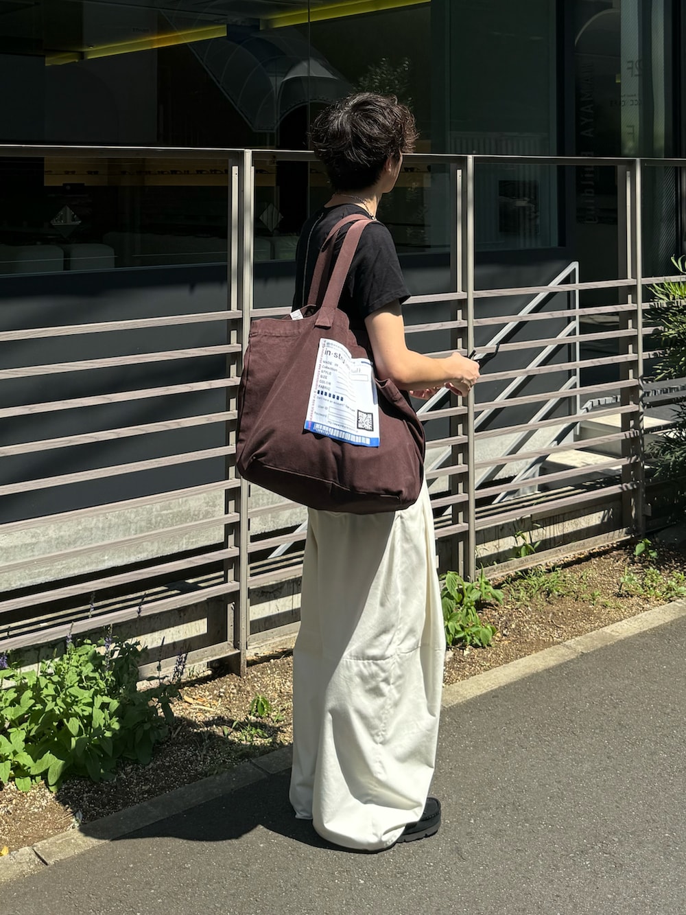 ホワイト系のその他パンツ、ブラウン系のトートバッグ、ブラック系のTシャツ/カットソーを着用したメンズの夏コーディネートの2枚目の写真