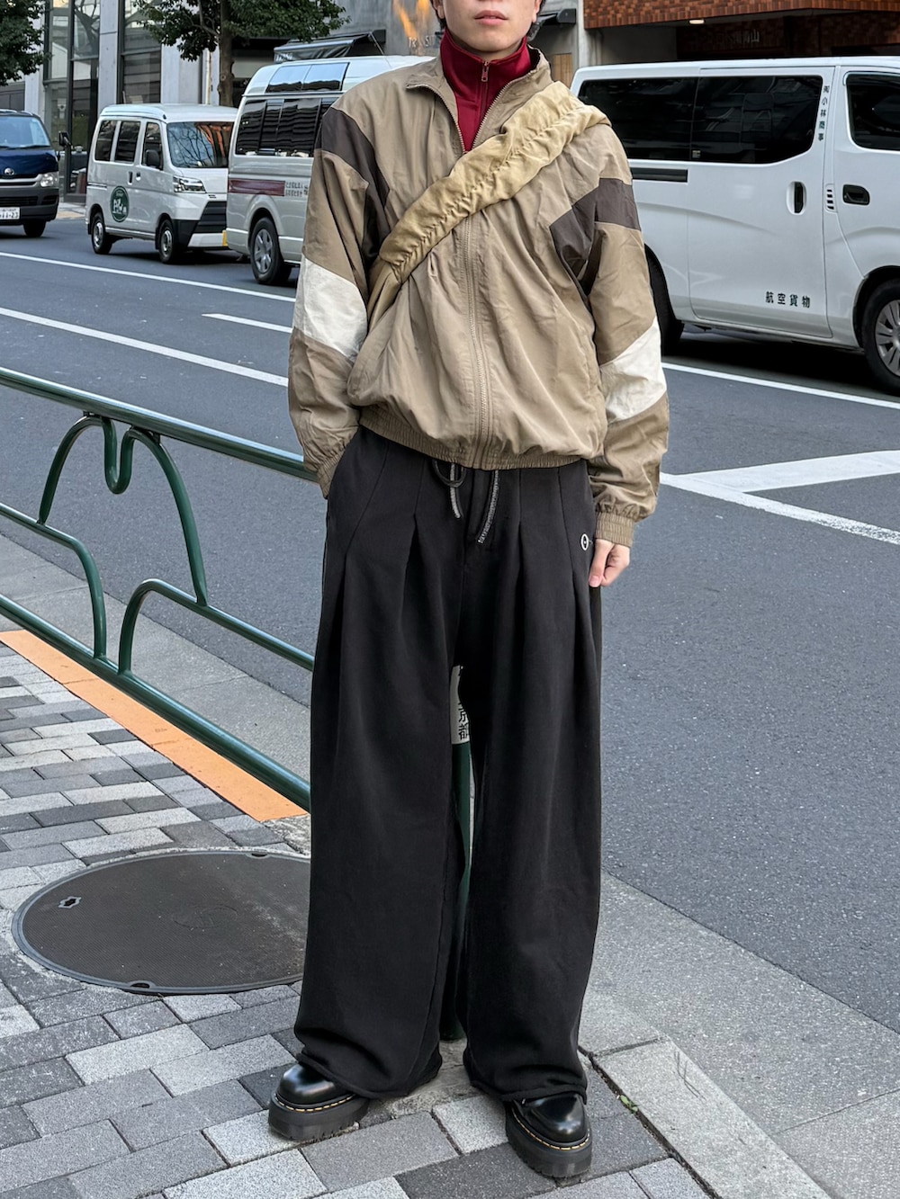 レッド系のその他トップス、ブラック系のブーツ、ベージュ系のナイロンジャケットを着用したメンズの春コーディネートの3枚目の写真