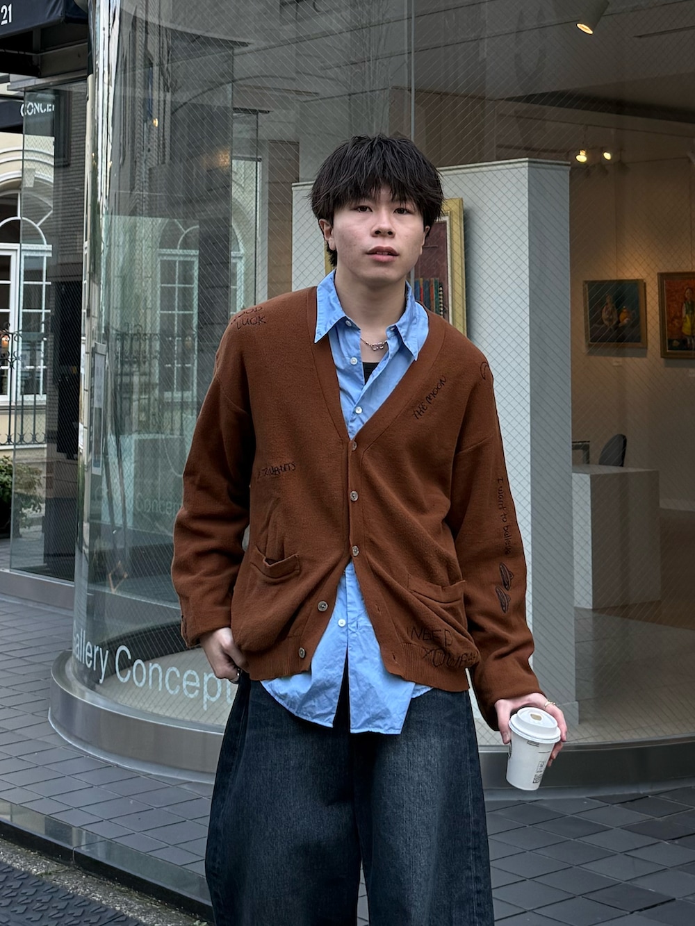 ブラウン系のカーディガン/ボレロ、ブルー系のデニムパンツ、ブルー系のスニーカーを着用したメンズの春コーディネートの2枚目の写真