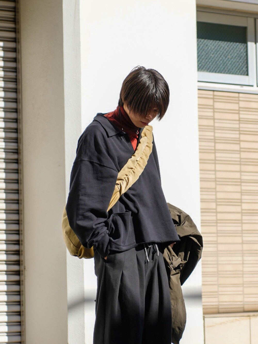 ブラック系のスウェット、ブラック系のスウェットパンツ、ベージュ系のショルダーバッグを着用したメンズの冬コーディネートの2枚目の写真