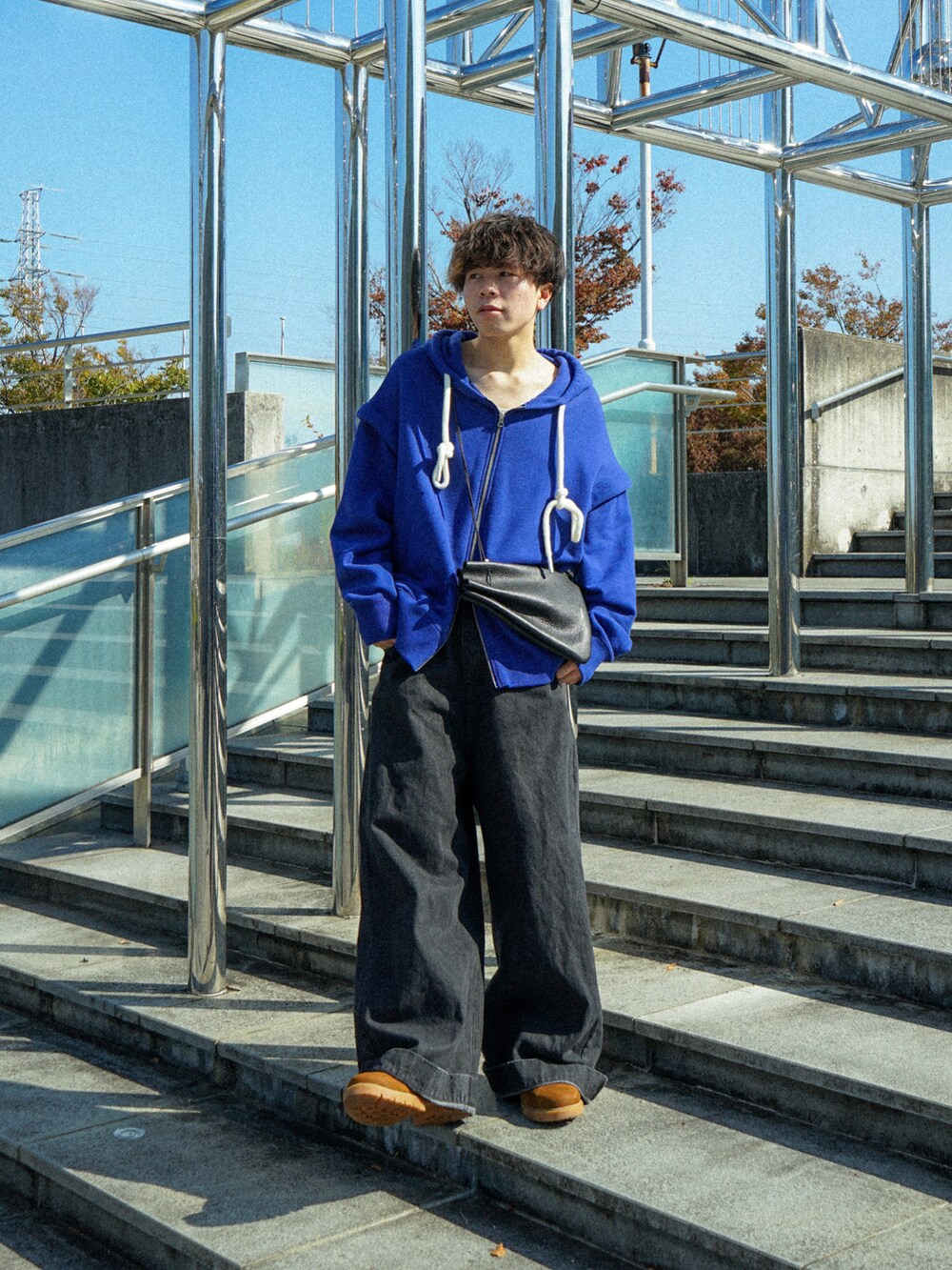 ブルー系のパーカー、ブラック系のデニムパンツ、ブラック系のショルダーバッグを着用したメンズの秋コーディネートの4枚目の写真