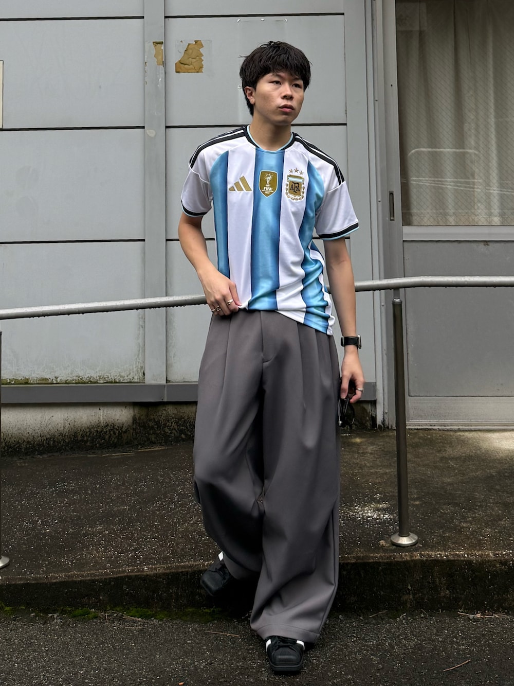 ホワイト系のTシャツ/カットソー、グレー系のパンツ、ブラック系のスニーカーを着用したメンズの夏コーディネートの2枚目の写真