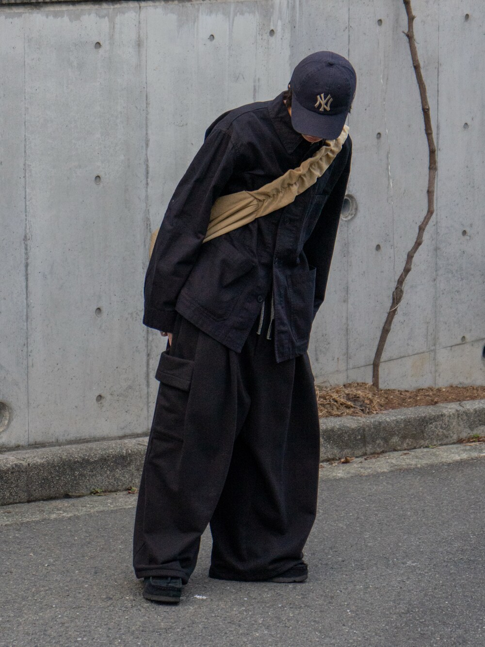 ブラック系のカバーオール、ブラック系のスウェットパンツ、ベージュ系のショルダーバッグを着用したメンズの冬コーディネートの2枚目の写真