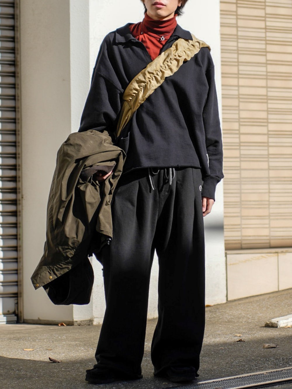 ブラック系のスウェット、ブラック系のスウェットパンツ、ベージュ系のショルダーバッグを着用したメンズの冬コーディネートの3枚目の写真