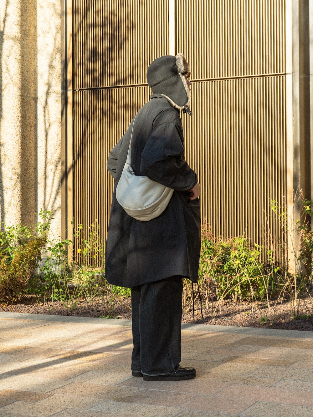 ブラック系のモッズコート、ブラック系のデニムパンツ、ブラック系のブーツを着用したメンズの冬コーディネートの2枚目の写真