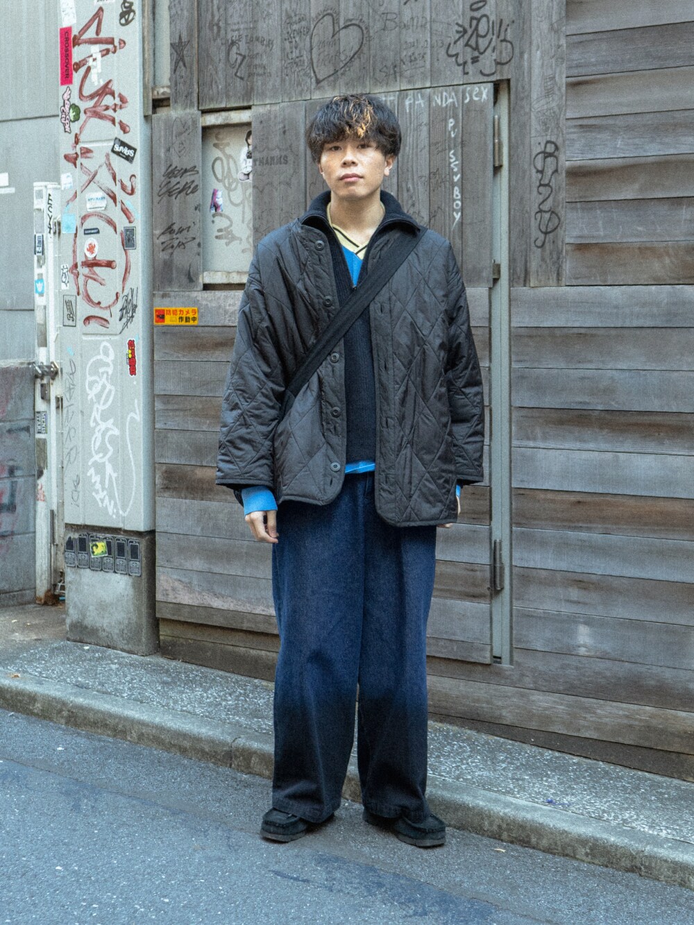 ブラック系のミリタリージャケット、ブルー系のニット/セーター、ブラック系のデニムパンツを着用したメンズの冬コーディネートの2枚目の写真