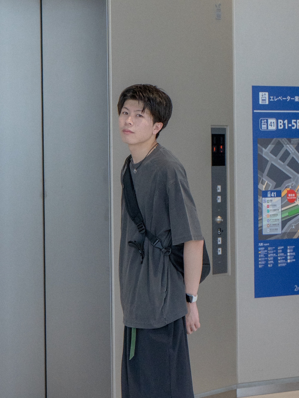 グレー系のTシャツ/カットソー、ブラック系のショルダーバッグ、ブラック系のスラックスを着用したメンズの夏コーディネートの4枚目の写真