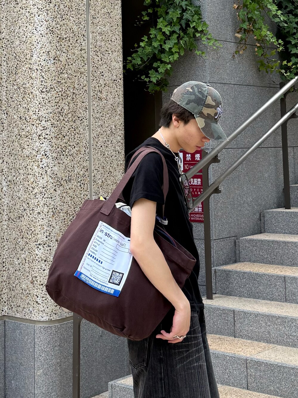 ブラック系のTシャツ/カットソー、グレー系のデニムパンツ、ブラウン系のトートバッグを着用したメンズの夏コーディネートの4枚目の写真