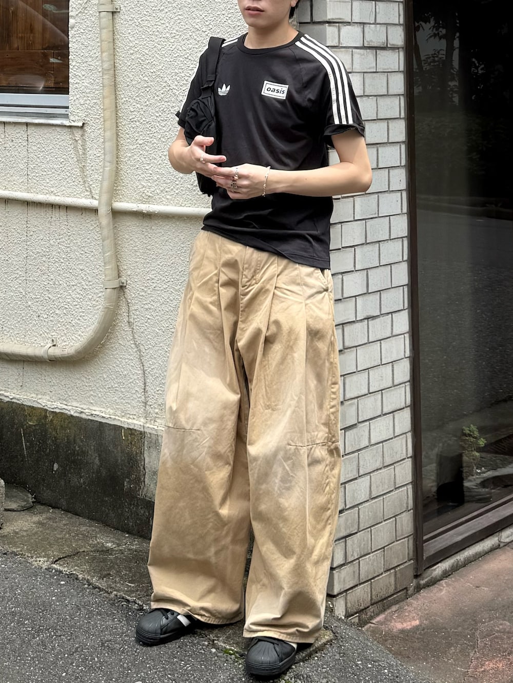 ブラック系のTシャツ/カットソー、ベージュ系のチノパンツ、ブラック系のスニーカーを着用したメンズの夏コーディネートの2枚目の写真