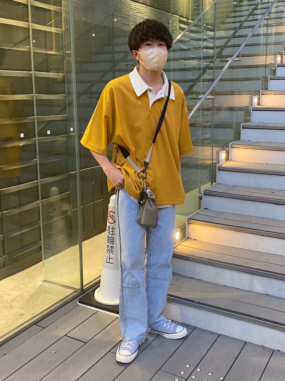 イエロー系のポロシャツ、ブルー系のデニムパンツ、ベージュ系のショルダーバッグを着用したメンズの夏コーディネートの2枚目の写真