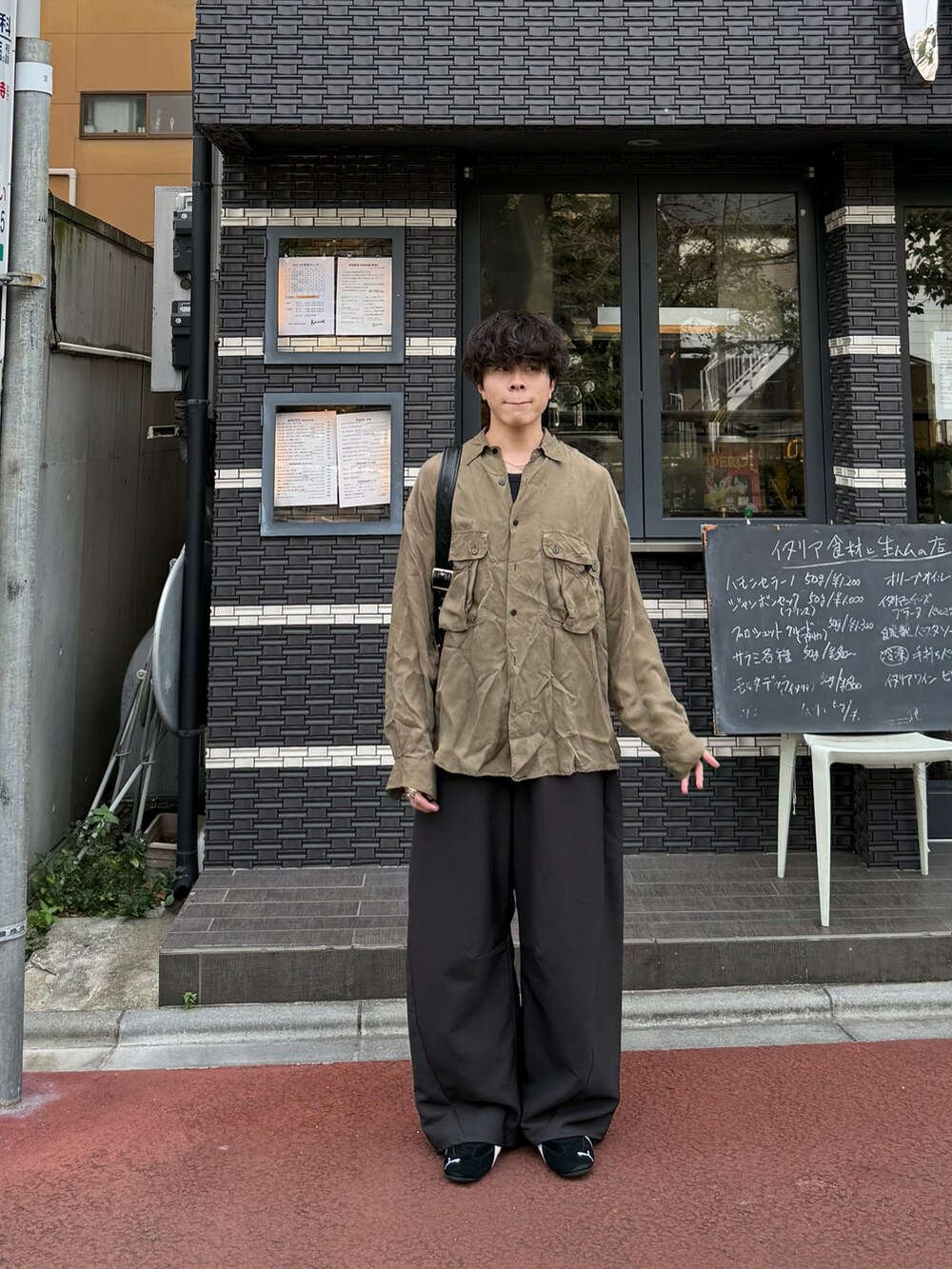 グレー系のスラックス、ブルー系のタンクトップ、ブラック系のショルダーバッグを着用したメンズの秋コーディネートの2枚目の写真