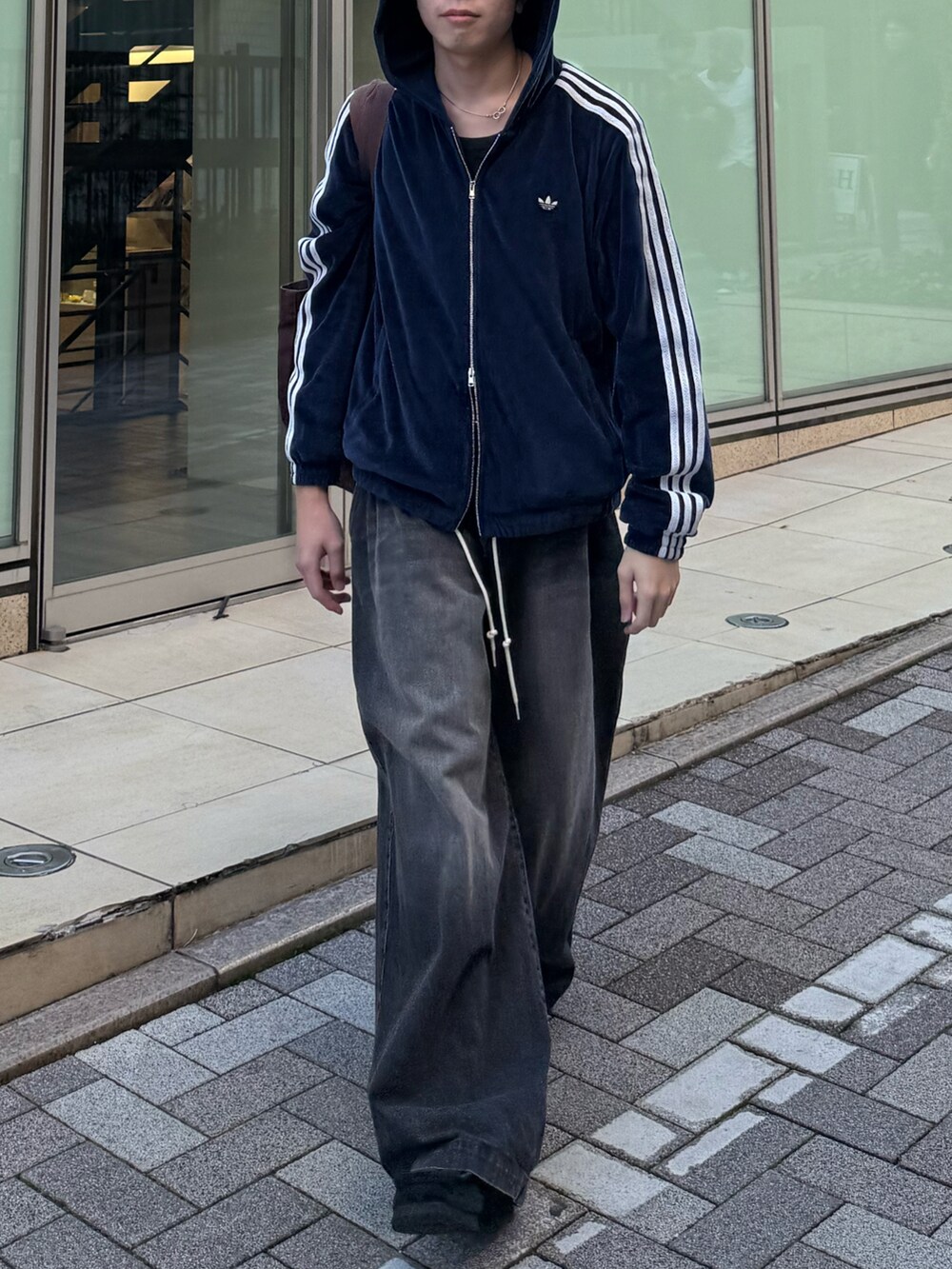 ブルー系のブルゾン、ブラック系のデニムパンツ、ブラウン系のトートバッグを着用したメンズの秋コーディネートの4枚目の写真